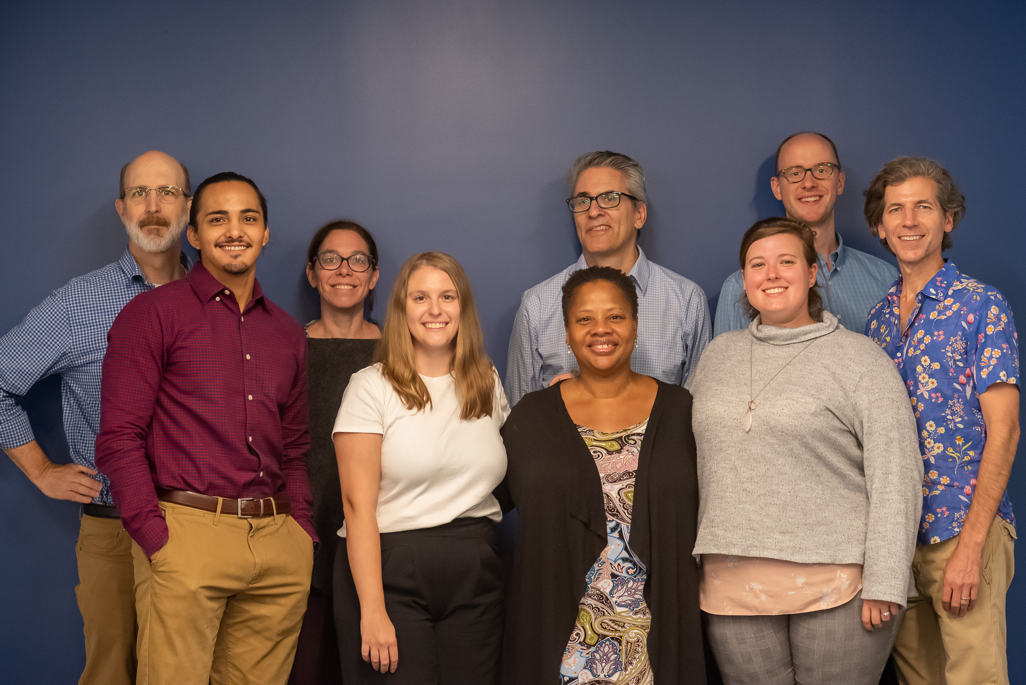 Nine staff members of the Georgetown Climate Center smile and pose for the camera against a blue background. 