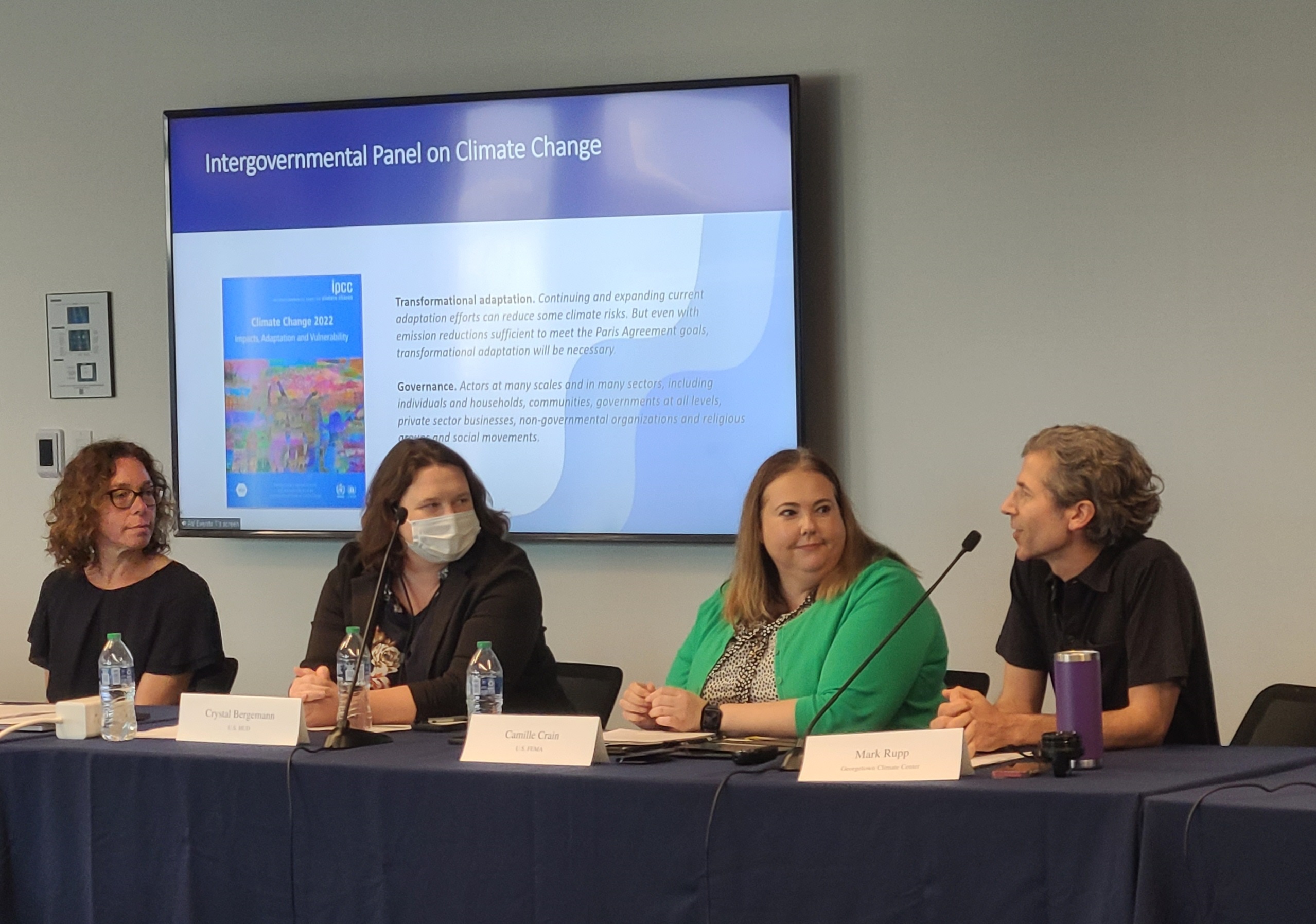 A panel of experts seated behind a table, speaking at microphones, with a powerpoint screen behind them. Speakers include GCC executive director at left, and GCC Adaptation Program director Mark Rupp at right. 