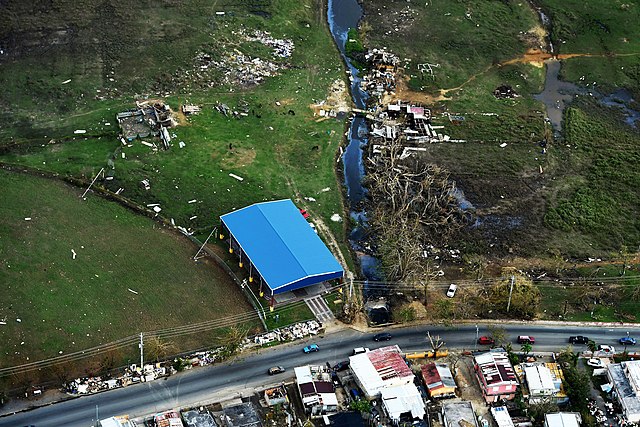 A blue shelter is the only remaining undamaged structure in a field in Puerto Rico where surrounding homes have been destroyed.