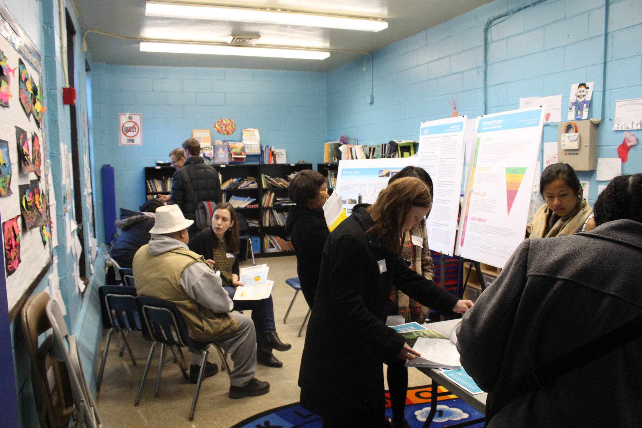 A woman leads a small discussion group of adults in a classroom, talking about resiliency strategies in Edgemere, NY