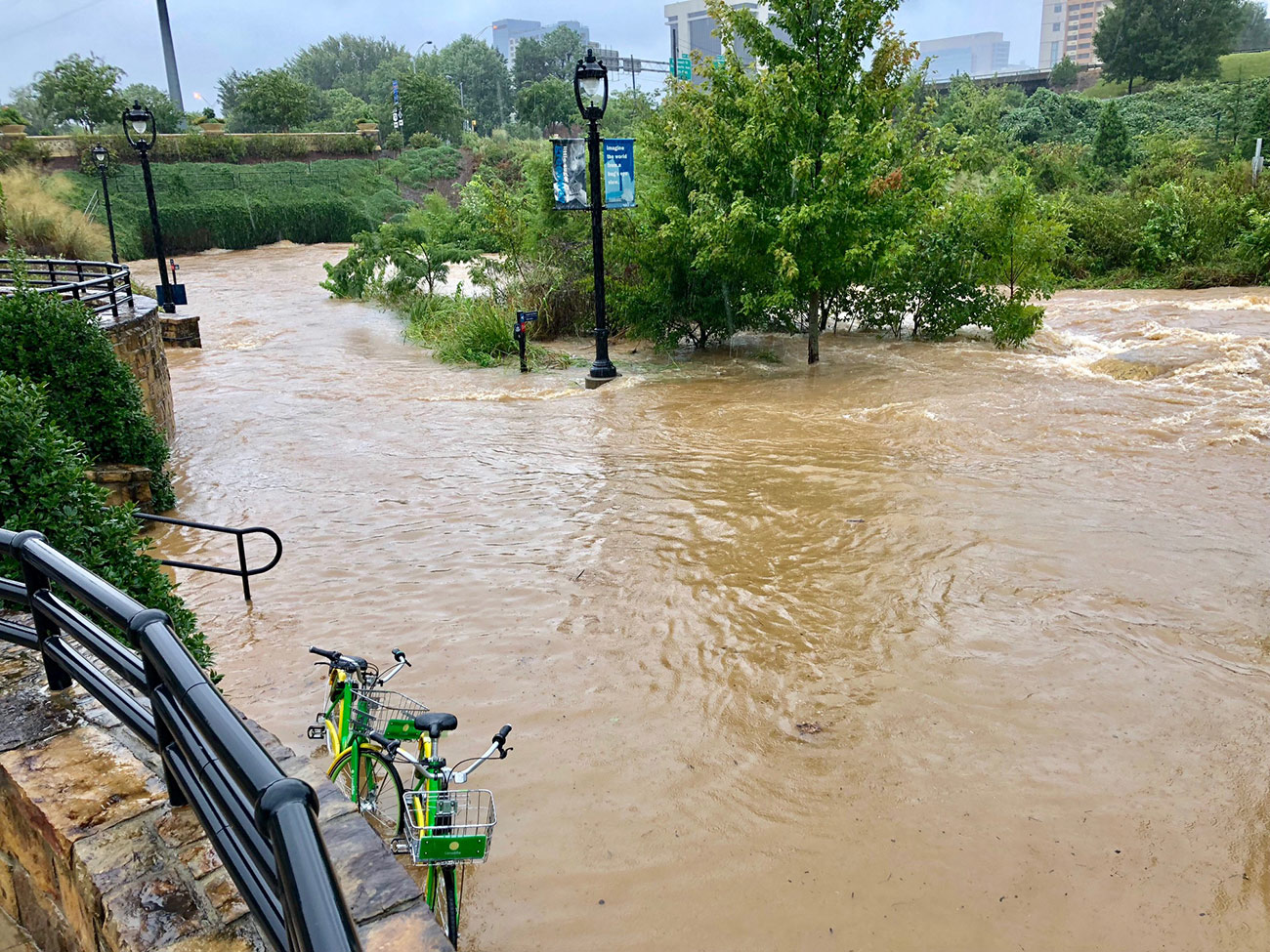 A flooded park in Charlotte after Hurricane florence. The water is so high that benches and paths are submerged. Streetlights and trees stick out of the water.