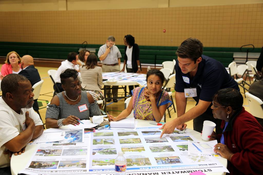 Five people of different races and backgrounds sit around a table at a public engagement meeting examining a series of charts.